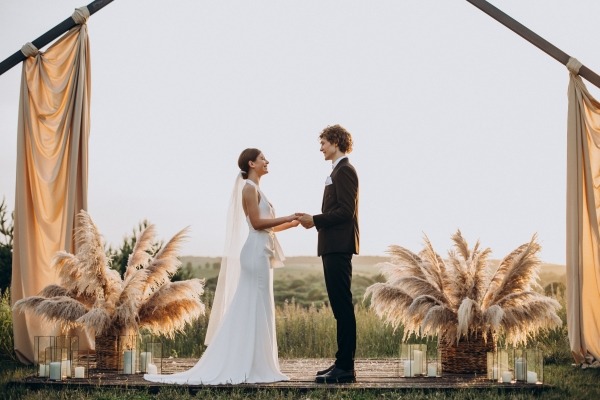 A bride and groom standing in front of a industrial chic wedding arch at sunset.