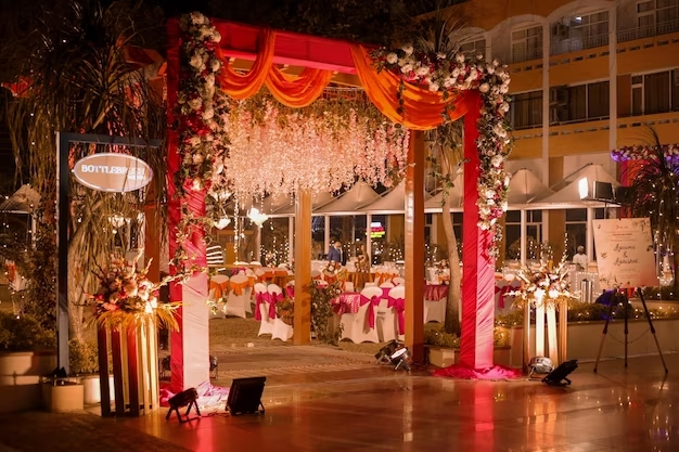 A whimsical wedding arch adorned with flowers and lights at night.