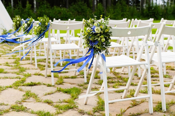 White chairs with blue ribbons at a rustic outdoor Wedding Decorations.