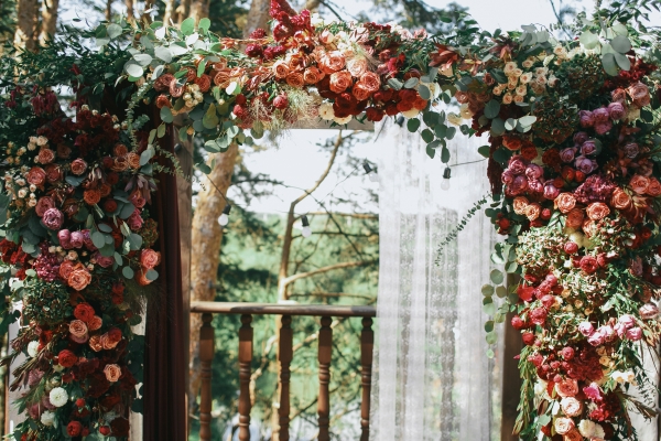 A wedding arch adorned with bohemian flowers and greenery.