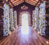 A wedding ceremony in a wooden church adorned with elegant white and yellow flower decorations.