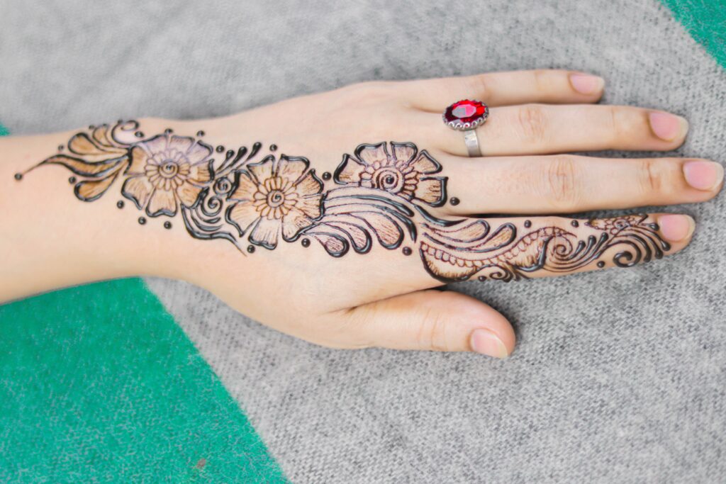 
A woman's hand with a floral Mehndi design on it.